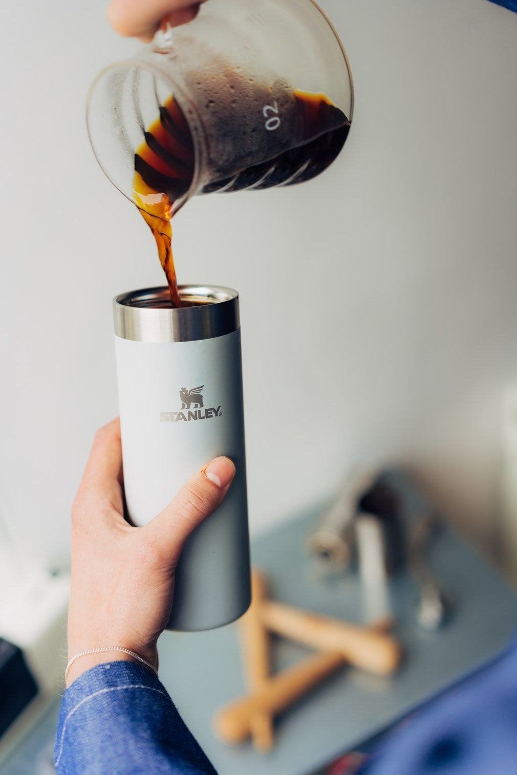 Fog Stanley Aerolight Transit Mug held in a hand while coffe is being poured into it from a glass jug